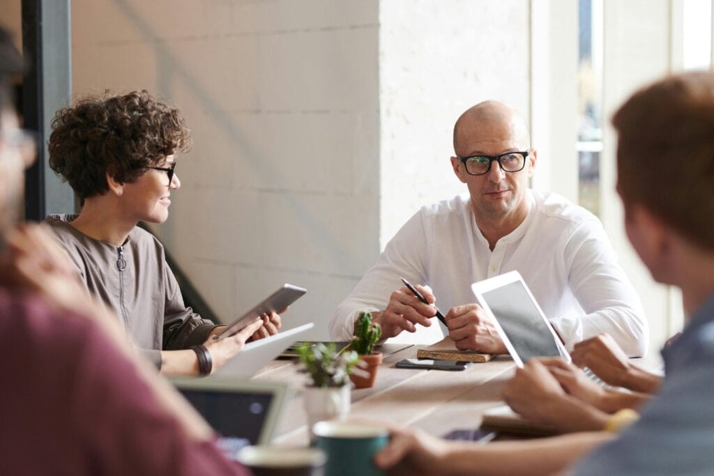 Liệu Nhà Đồng Sáng Lập Quan Trọng Thế Nào? 2 Group of professionals engaged in a brainstorming session around a table in a contemporary office space.