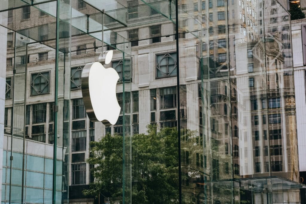 Làm sao để tăng độ nhận diện thương hiệu trong giai đoạn đầu? 2 Apple logo on a modern glass facade with urban reflections, capturing contemporary architecture.